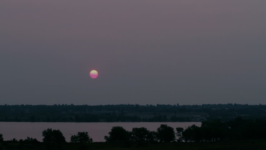 Mysterious red sun rises over landscape with lake. HD 1080p time lapse.