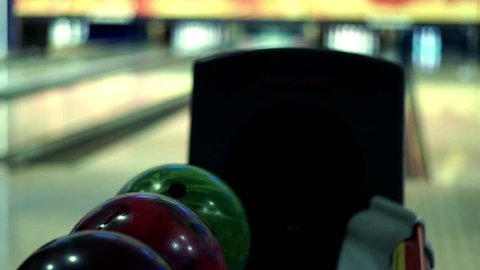 Bowling game. Bowling balls lie on stand close up. Player holds bowling ball with hand