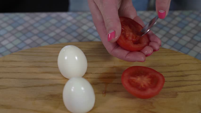 Close-Up of Hands of a Young Girl With Painted Fingernails Removed With a Spoon the Insides of the Two Halves of the Tomato,then Put the Two Halves Next to Tomatoes on the Kitchen Board With the