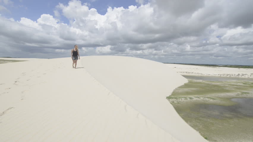 blonde girl walking on a dune in Jericoacoara, Brazil