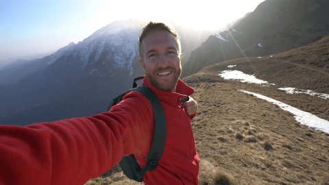 Young man hiking in Switzerland takes selfie on top of mountain.
Hiker reaches mountain top takes self portrait 