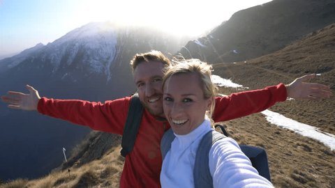 Young adventurer couple hiking in Switzerland, taking selfies on mountain top at sunset