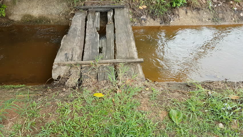small old wooden bridge on a concrete channel 