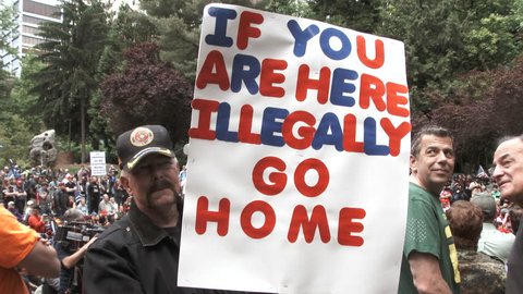 JUNE 4TH, 2017 - PORTLAND, OREGON: Man holding sign reading "If you are here illegally, go home," supporting Donald Trump's travel ban at Republican rally.
