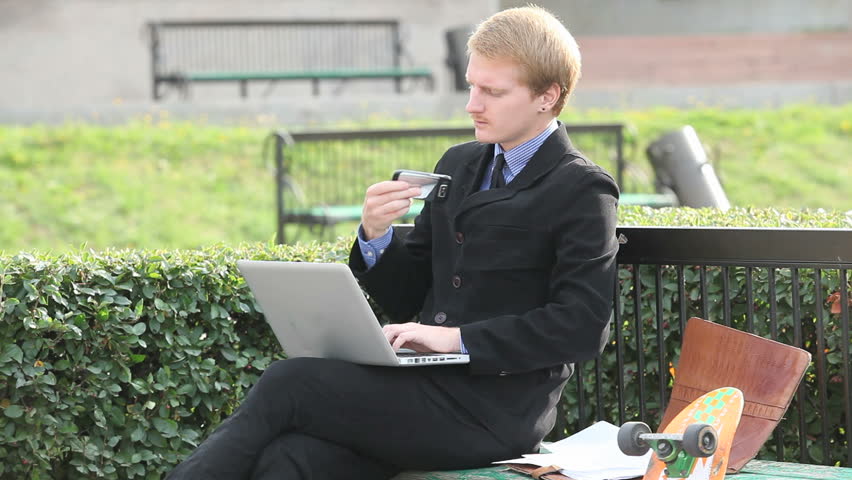 Successful businessman working at laptop and sitting on the bench