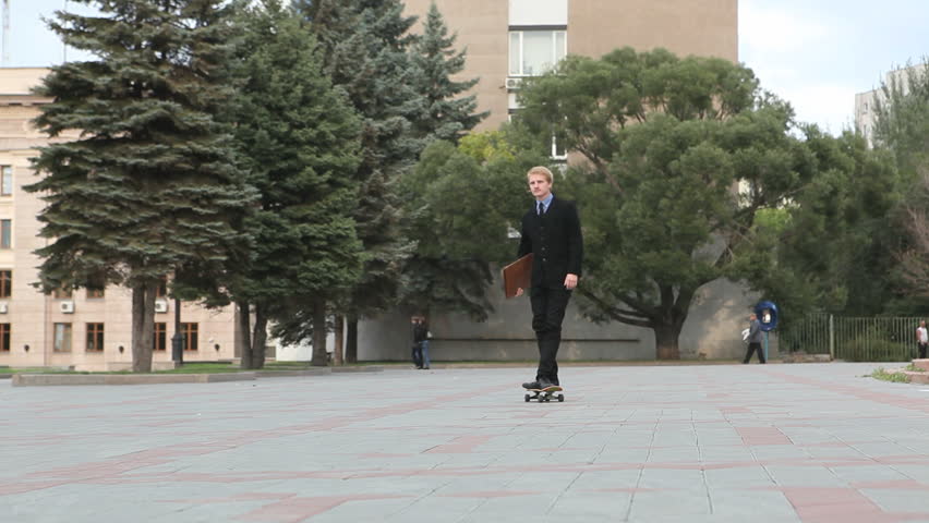 Confident businessman having fun on skateboard outdoor
