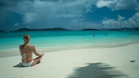 Timelapse of a woman meditating on a tropical beach in the Caribbean