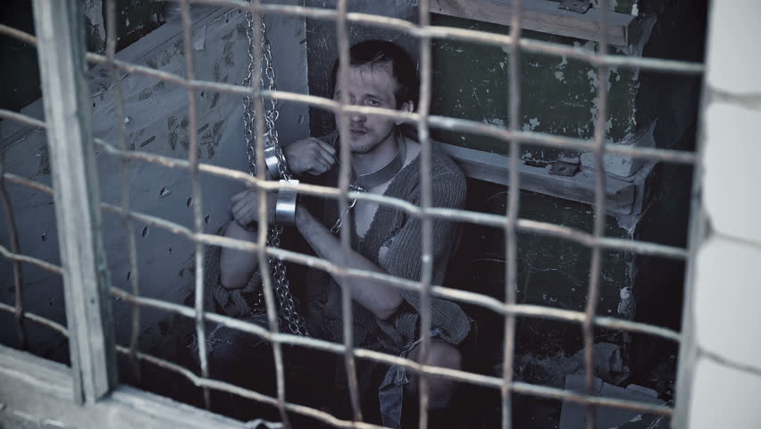prisoner behind bars sitting chained Royalty-Free Stock Footage #27538054