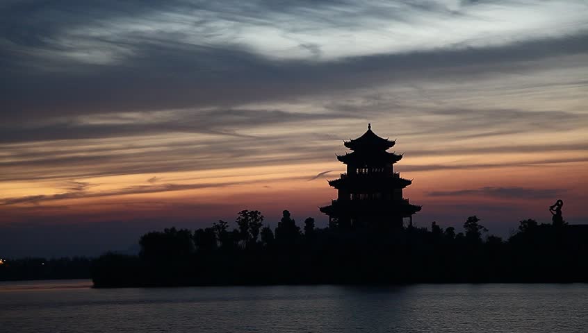 sunset in a lake near an ancient chinese tower building