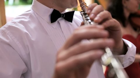 Musician plays the flute. Flutist professionally playing the flute in the wedding party