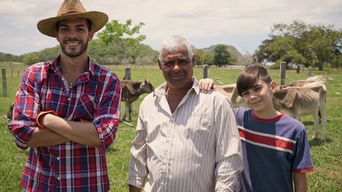 Everyday life for farmers with cows in Latin American countryside. Peasants work with livestock in family country ranch. Manual job and people in farm. Happy grandfather, dad and child smiling