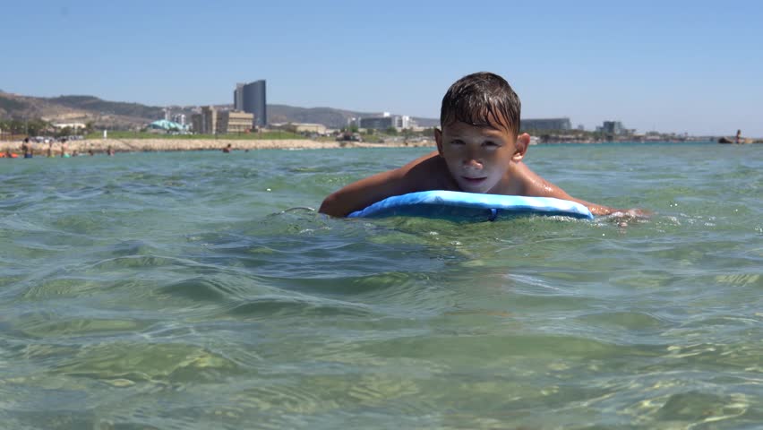  a boy on the board swims on the sea