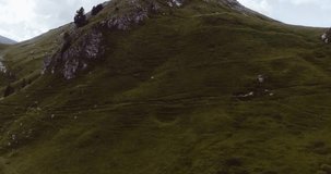 Aerial flight above mountain top in overcast cloudy weather. Summer adventure journey in mountain nature outdoors. Travel exploring Alps, Dolomites, Italy. 4k drone forward video