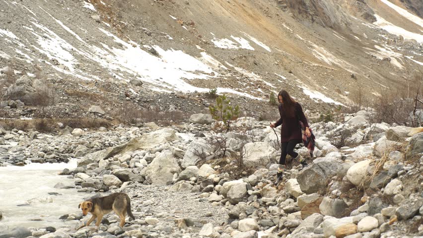 beautiful young traveler walks along the mountain river,mountains in the background