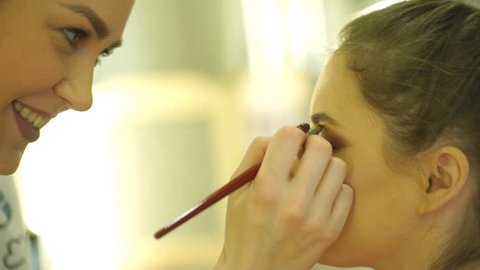 Process of making makeup. Make-up artist working with brush on model face.