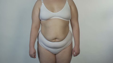 Overweight woman wearing undies posing for camera and turning around, obesity