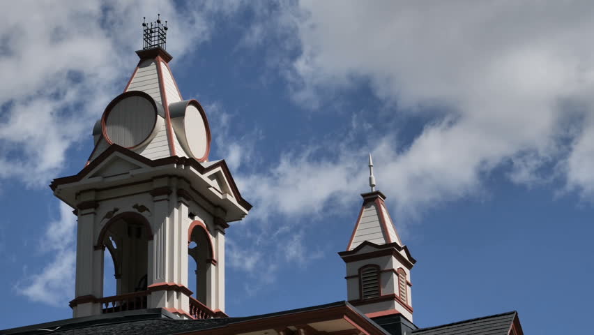 Time Lapse-White clouds against a blue sky blow past old circa 1874 school bell tower lighted by morning light