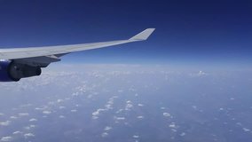 Airplane wing with turbine and blue sky with white clouds, mobile phone video.