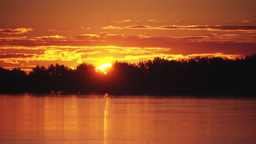 Orange sunrise on top of forest at the river