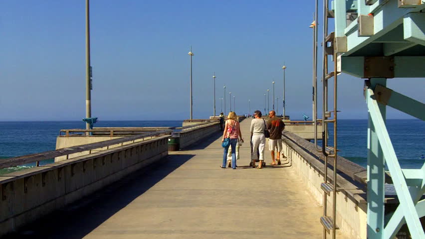 In the distance, people walk on the fishing pier at Venice Beach, CA. . 