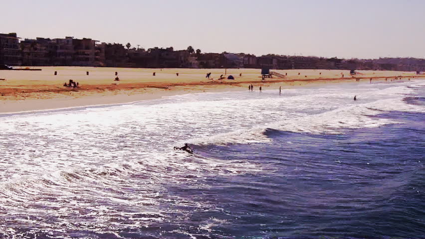 In the distance, a Southern California surfer paddles out into the Pacific Ocean