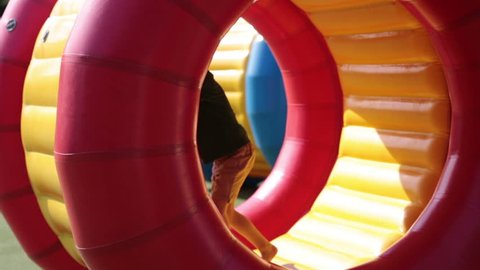 Cute little boys, playing in a rolling plastic cylinder ring with a hole in the middle, outdoor