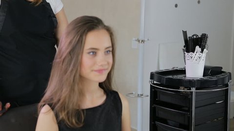 Hairstylist, hairdresser prepares teen girl in white make up room for hairdressing