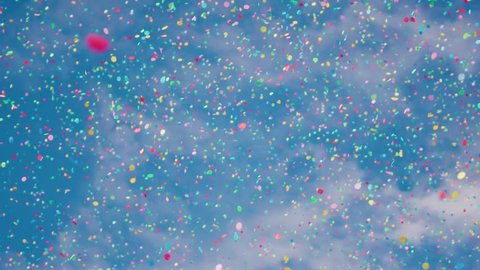 Falling confetti against a summer blue sky. Shot in slow motion