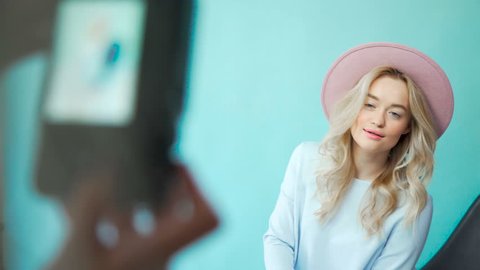 Behind the scene: model girls are posing for a photographer in gentle dresses and pink hat. Backstage: photographer takes pictures of the model in dresses. The process of work of professional model
