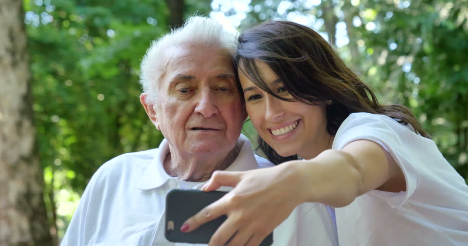 Granddaughter, a nurse, caring for the elderly, a girl (woman) and grandfather, do selfie, happy, smiles, in the park. Concept boarding house, sanatorium, house for the elderly, help for the elderly | Shutterstock HD Video #27590932