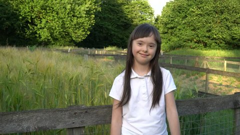 Down syndrome girl giving thumbs up and smiling in the park