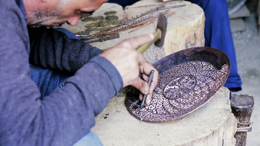 Traditional tinsmith work. Copper smith makes embossing artifacts from copper. Designing utensils, the age old art of crafting wares. Copper engraving. Souvenirs. Shooting close-up Copper smith work.