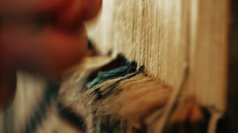 Carpet weaving.  Turkish woman weaving a carpet with peace of genuine camel wool with a manual waving machine. Needlework. Carpet-makers work close-up video.

