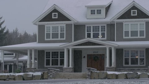 Country home in winter storm with snow falling.