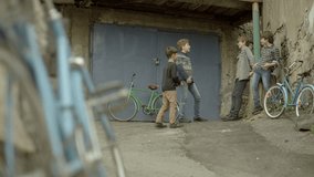 Happy Friends standing and talking with each other near old garage with bicycles. Vintage times. Childhood Memories. Shot on RED EPIC DRAGON Cinema Camera in slow motion.