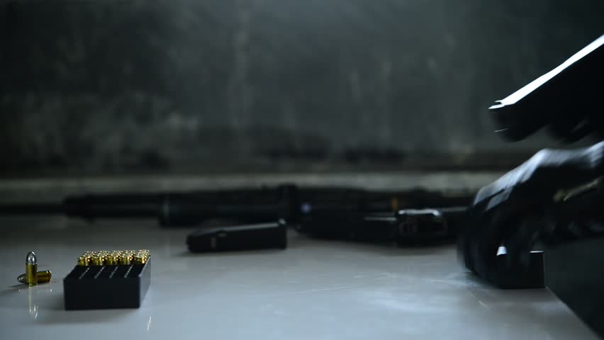 Asian male wearing black leather gloves with gun in hand,loading bullets to gun