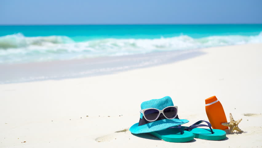 Beach accessories - straw hat, flip flops, bottle of cream and sunglasses on the beach Royalty-Free Stock Footage #27600694