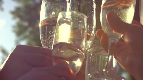 Group of people toasting and drinking champagne on the restaurant terrace over sunset. Celebrating. Glasses with Sparkling Champagne over nature Background. Resort. 4K UHD video 3840X2160 