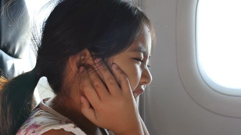 4K : Nervous little Asian girl covering ears with hands because of jet loud noise and fright