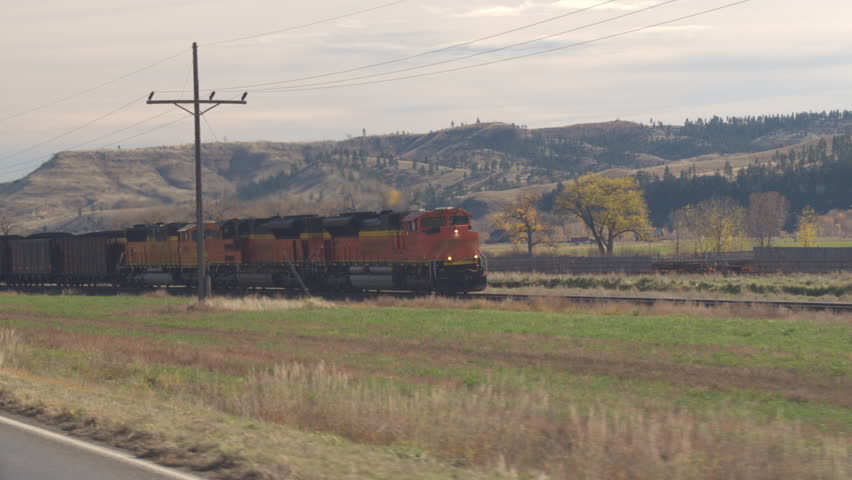 BILLINGS, MONTANA - 30th OCTOBER 2016: CLOSE UP Locomotive hauling freight train wagons loaded with coal along the hilly landscape across America. Train moving on railroad tracks transporting goods