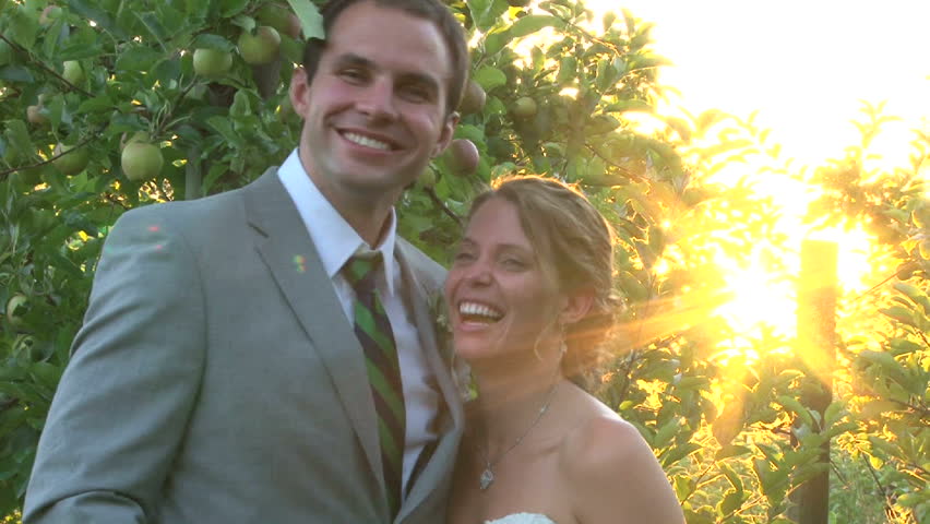 Model released bride and groom laughing together at sunset on their wedding day.