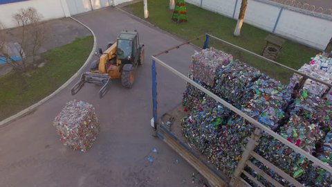 The loader loads the trailer with bales of compressed plastic. Aerial view. Drone view. Drone footage. 4K. Processing of plastics. Renewable energy sources.