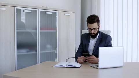 Businessman typing on his phone while sitting in office
