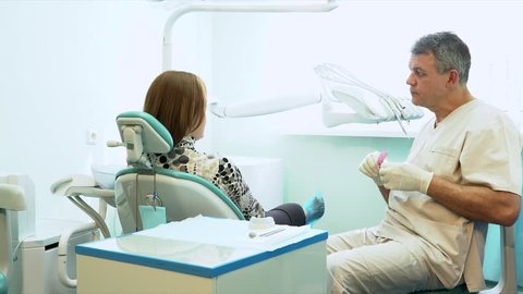 The kind man the dentist talks in a light office to the patient