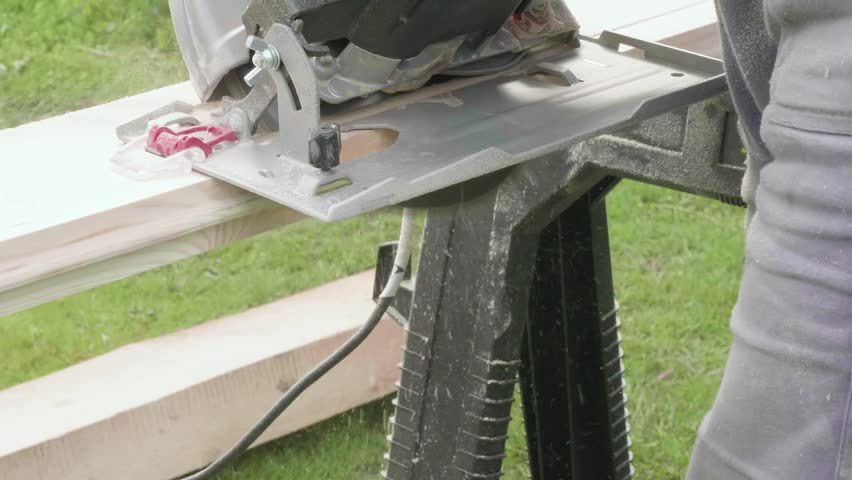 Carpenter cuts board with circular saw. Slow motion view.