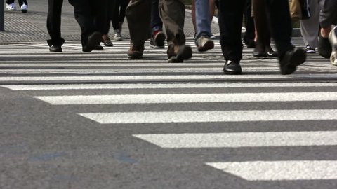 People step across a road by crosswalk or zebra crossing / Pedestrian crossing in a city