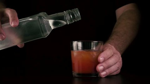 The barman's hands pour frozen vodka into a glass with tomato juice. Cocktail bloody mary. Slow motion