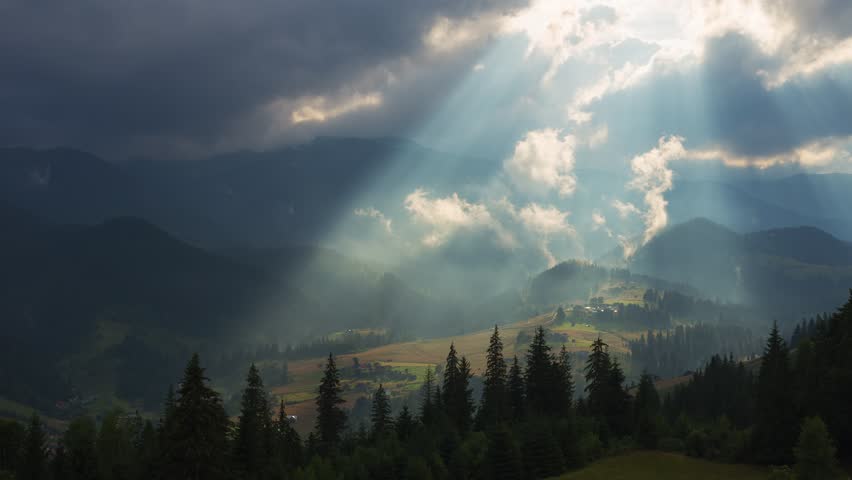 Timelapse of sun rays emerging though the dark storm clouds in the mountains with pine tree forest on a foreground Royalty-Free Stock Footage #27627829