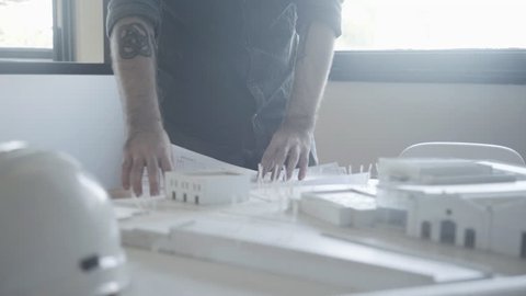 Architect looking at blueprint and architectural model