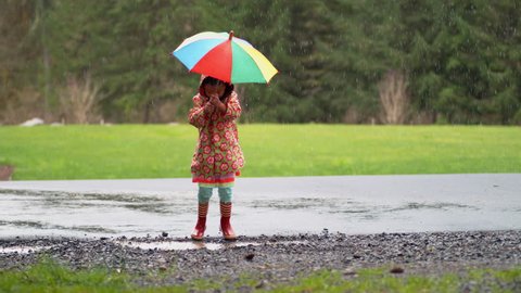 Young girl with umbrella playing in rain, slow motion, shot with Phantom Flex 4K